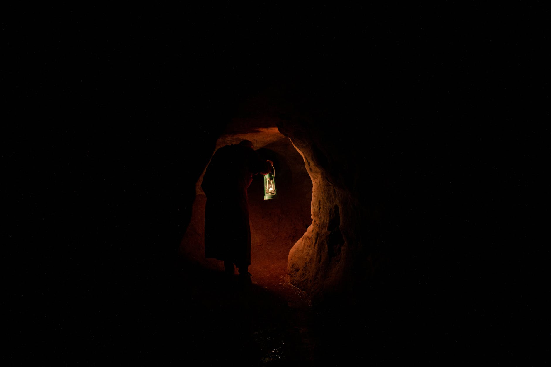a person holding a lamp in a dark cave